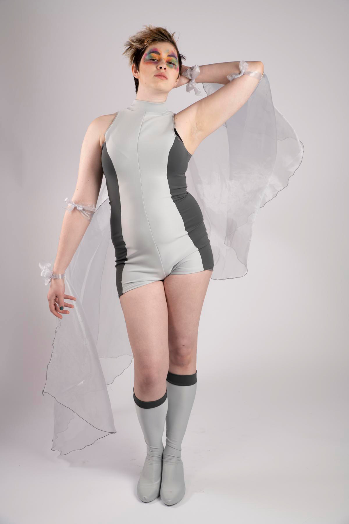 Jax Joel models a soft cloud grey and slate grey boyshort style bodysuit with knee-high boots and silver mirror organza.