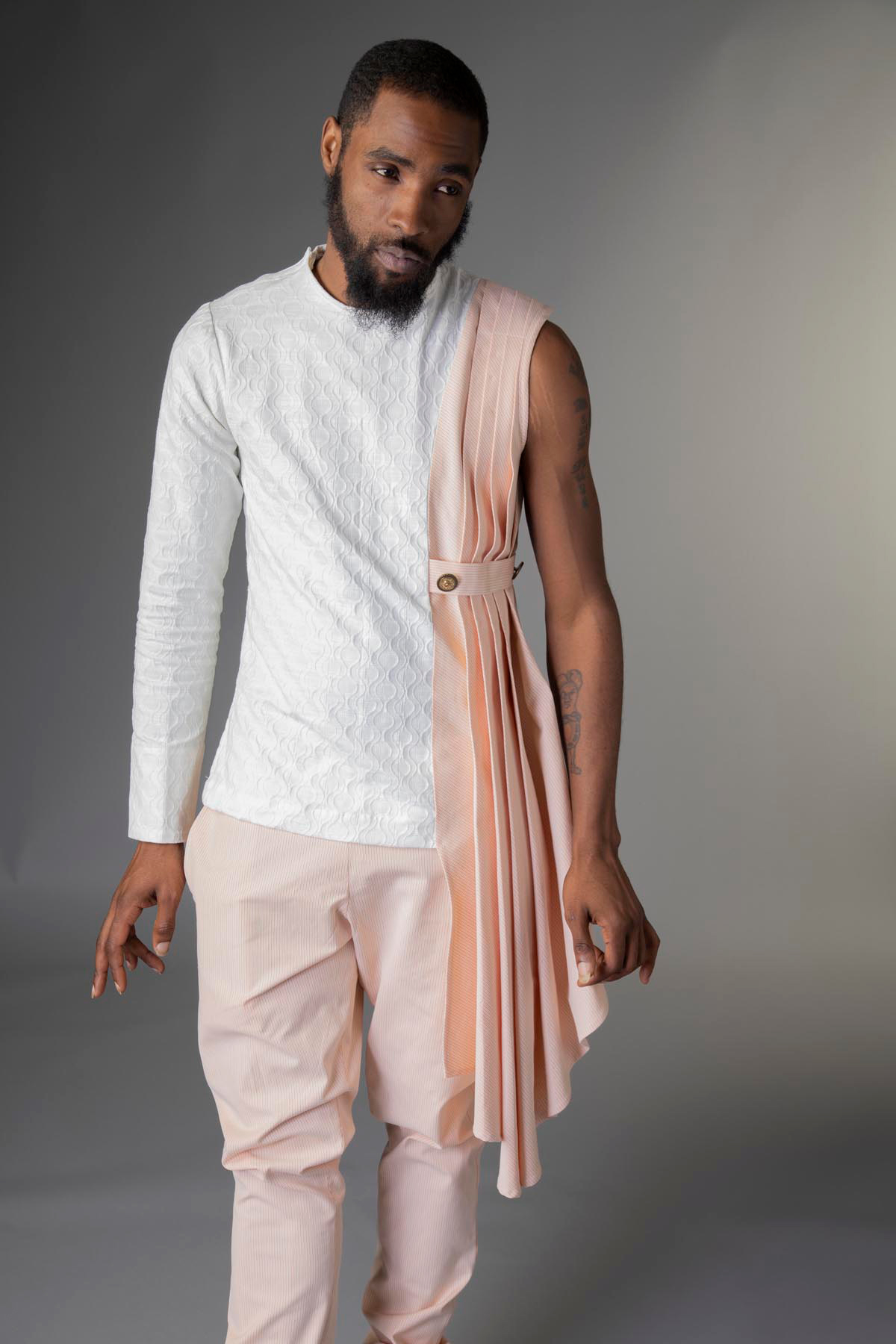 Male models a man’s avant-garde suit with asymmetric drape and pants.