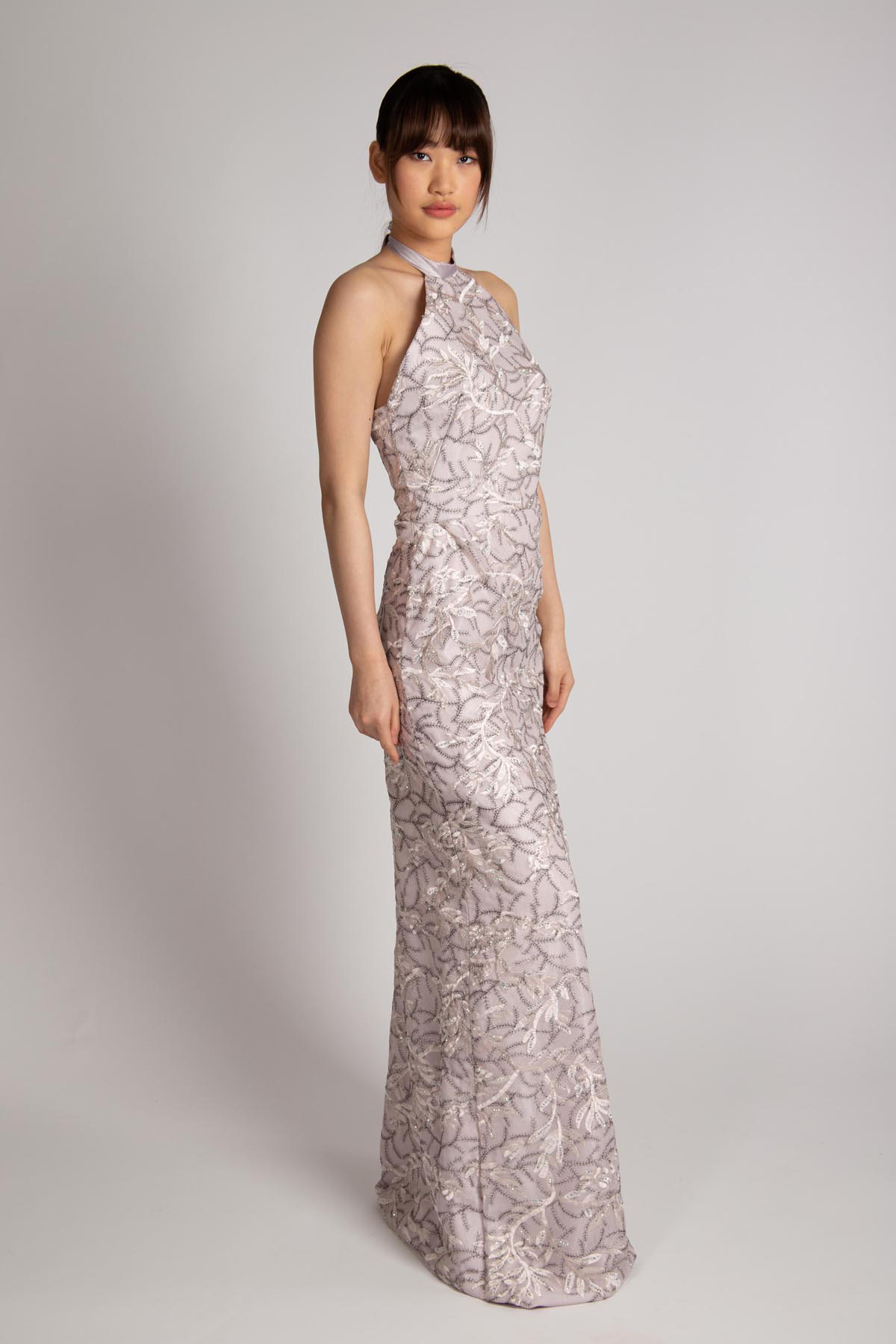 Hongman Li models a silver violet evening gown with low cut back made of tulle with embroidery.