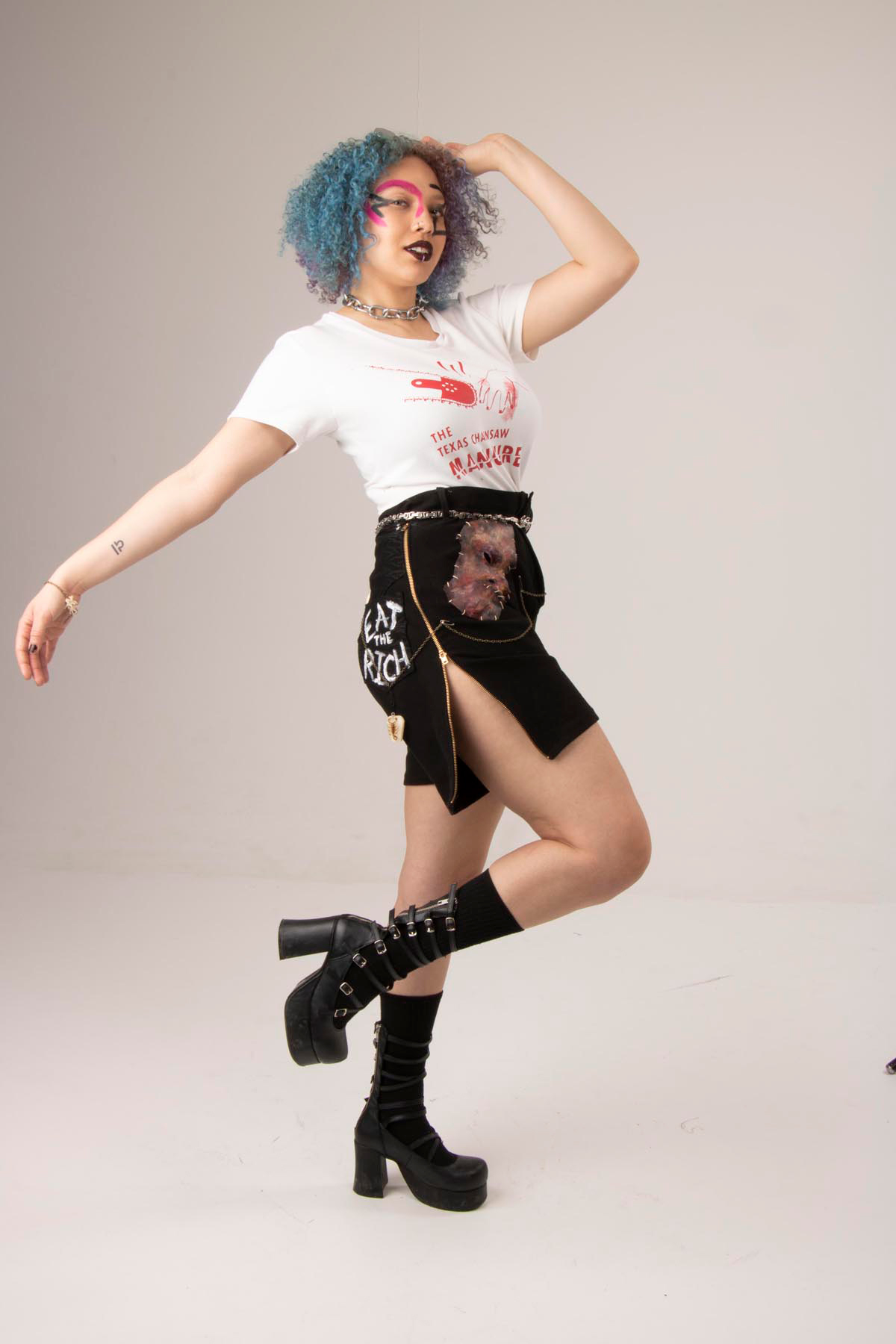 A white knit tee with a screen printed design, paired with black denim
                high-waisted shorts, appliquéd with molded leather faces and hand-painted quips on the back.